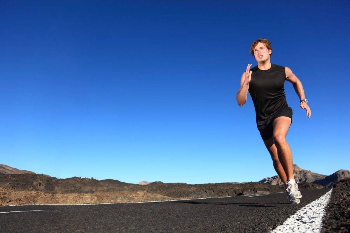 a man running on a road with a blue sky