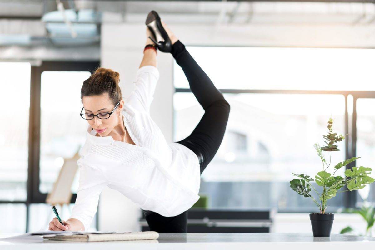 Happy woman making notes while standing near desk in cozy apartment. She making physical jerk near it